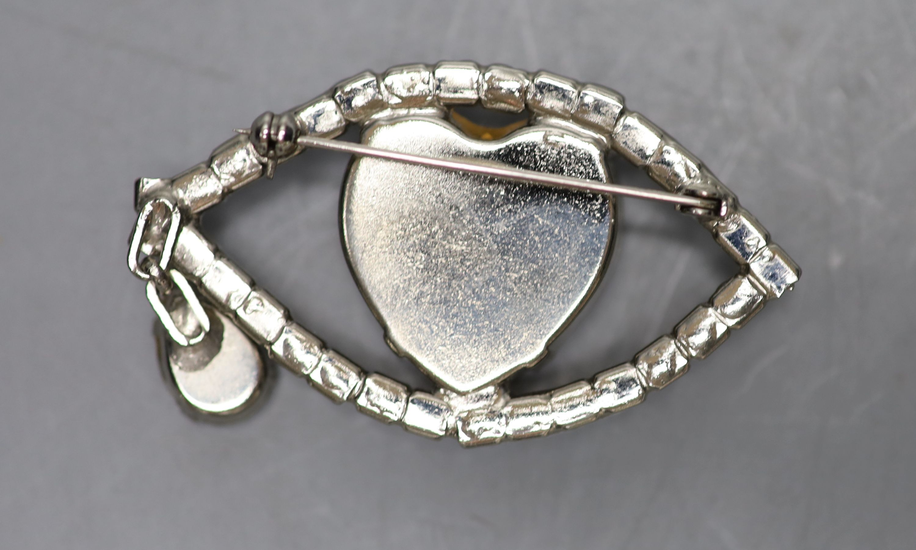 A base metal and white paste set 'eye' drop brooch, width 61mm.